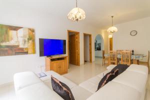 uma sala de estar com um sofá branco e uma televisão de ecrã plano em Cotswold Sea Apart with 3 bdr at Qawra - Happy Rentals em St. Paul's Bay