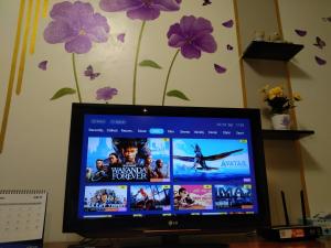 a computer monitor sitting on a desk with purple flowers at QQ Homestay in Ipoh