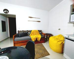 uma sala de estar com um sofá e um cobertor amarelo em Apartamento Ubatuba Maranduba 150m da Praia em Ubatuba