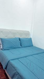 Easy Homestay في Mukah: سرير مع وسائد زرقاء في الغرفة