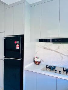 Easy Homestay في Mukah: مطبخ مع ثلاجة سوداء ودواليب بيضاء
