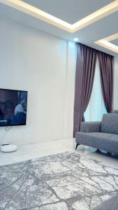 Easy Homestay في Mukah: غرفة معيشة مع أريكة وتلفزيون على الحائط