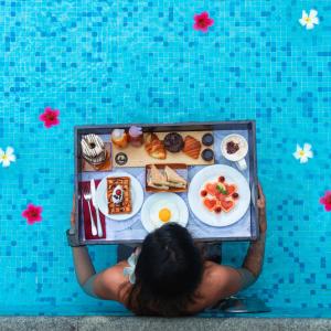 a person holding a tray of food in a pool at Four Points by Sheraton Mahabalipuram Resort & Convention Center in Mahabalipuram