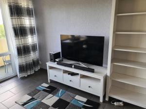ein Wohnzimmer mit einem Flachbild-TV auf einem weißen Entertainment-Center in der Unterkunft Großzügige Ferienwohnung E328 an der Ostsee in Brasilien