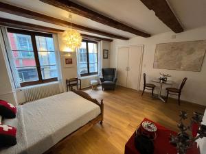 a bedroom with a bed and a chair and a table at Le studio Suisse au cœur de Neuchâtel in Neuchâtel