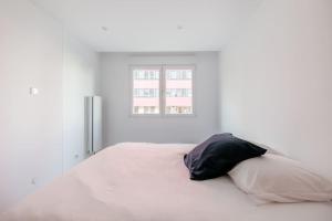 a white bedroom with a large bed with a pillow at Le Wilson 13A - Joli appt refait à neuf in Strasbourg