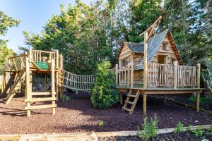 two wooden playhouses in a yard with trees at Period Luxury Converted Barn Windsor/Maidenhead - Perfect for family groups in Taplow