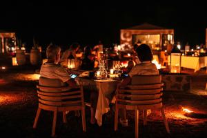 un gruppo di persone sedute a un tavolo di notte di Merzouga luxury desert camps a Merzouga