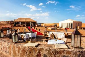 un restaurant dans le désert avec des tables et des chaises dans l'établissement Merzouga luxury desert camps, à Merzouga