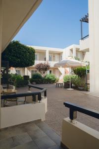 a courtyard with benches and tables and an umbrella at Corinna Mare in Kalamaki Chanion