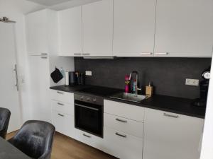 a kitchen with white cabinets and a sink at Am Boulevard in Gengenbach