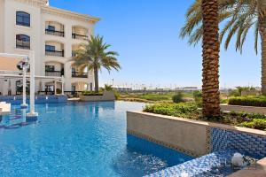 a swimming pool in front of a building with palm trees at WelHome - Luxury Apt Close to Yas Water and Ferrari World in Abu Dhabi