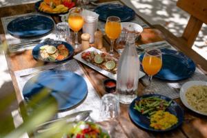uma mesa de madeira com pratos de comida e copos de sumo de laranja em Dhiffushi Inn em Dhiffushi