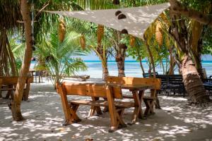 uma mesa de piquenique com um guarda-sol na praia em Dhiffushi Inn em Dhiffushi