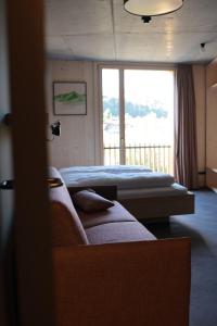 1 dormitorio con 2 camas, sofá y ventana en Story Thusis en Thusis