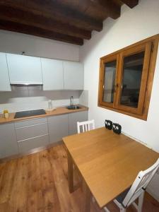 Una cocina con una mesa de madera y una cocina con gabinetes blancos. en Gigantones, en Toledo 3 fotos más
