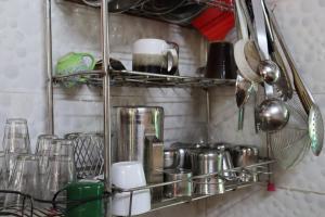 półka w kuchni z okularami i przyborami kuchennymi w obiekcie Da Mantra House w mieście Tiruvannamalai