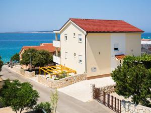 een wit gebouw met een rood dak naast de oceaan bij Apartments Cikač II - modern apartments by the beach in Mandre