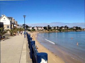 a beach with a blue fence and people in the water at TAMA in Saint-Lunaire