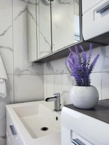 baño con lavabo y jarrón con flores púrpuras en Stara Pošta Apartment 1, en Grosuplje
