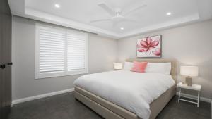 a white bedroom with a bed and a window at Amazing Views and Short Walk To Beach in Terrigal