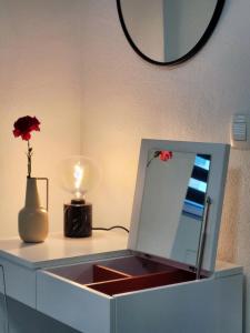 un tocador con espejo y un jarrón con flores. en Stara Pošta Apartment 1, en Grosuplje