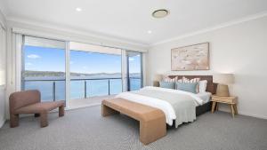 a white bedroom with a bed and a large window at Waters Edge - Point Clare - Pool - Spa - Private Jetty in Point Clare