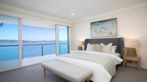 a bedroom with a large bed and a large window at Waters Edge - Point Clare - Pool - Spa - Private Jetty in Point Clare