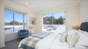 a bedroom with a bed and a large window at Waters Edge - Point Clare - Pool - Spa - Private Jetty in Point Clare