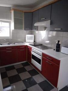 a kitchen with red cabinets and a white stove top oven at Appartement Cosy avec Terrasse in Vaux-sur-Seine