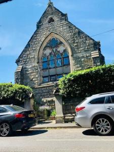 dos autos estacionados frente a una iglesia de piedra en Chapter Two - Melbourne en Melbourne