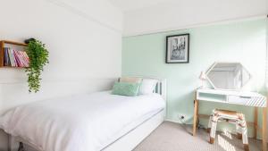 a bedroom with a white bed and a desk at Bangalow Beach House - Ettalong, pet friendly, walk to beach,shops,cafes in Ettalong