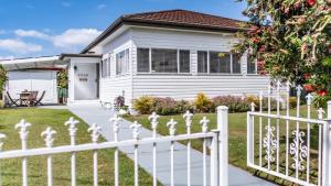 a white fence in front of a house at Bangalow Beach House - Ettalong, pet friendly, walk to beach,shops,cafes in Ettalong +9 photos