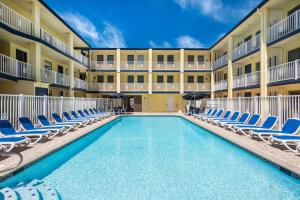 Days Inn by Wyndham Ocean City Oceanfront في آوشين سيتي: مسبح في ساحة منتجع مع كراسي جلوس