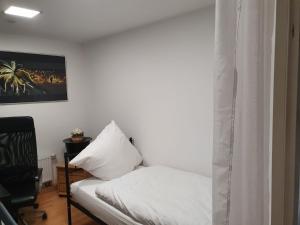a bedroom with a white bed and a black chair at Ferienwohnung/Montagewohnung in Paderborn