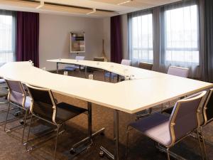 une salle de conférence avec une grande table blanche et des chaises dans l'établissement Novotel Metz Centre, à Metz