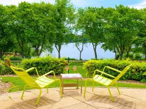 3 gelbe Stühle und ein Tisch im Park in der Unterkunft Novotel Paris Créteil Le Lac in Créteil