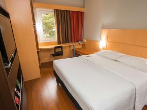 a bedroom with a large white bed and a desk at ibis Asuncion in Asuncion