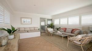 a living room with couches and chairs and windows at Beach Vibes at Terrigal in Terrigal