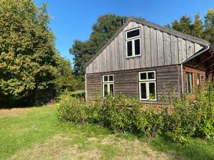 una vecchia casa in legno in un campo alberato di Brour&Bos a Laren