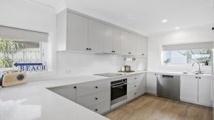 a white kitchen with white cabinets and a sink at Tatala in North Avoca