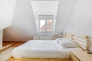 a white bedroom with a bed and a window at Le Bâle in Strasbourg