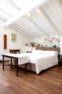 Cama blanca grande en habitación con suelo de madera en Agrirėlais Eremo Sant’Anna, en Valverde