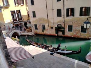 a man in a gondola in a canal between two buildings at Dimora Al Doge Beato vista canale in Venice