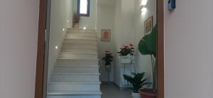 una escalera con escaleras blancas en una habitación con plantas en La Terrazza sul Golfo, en Sennori