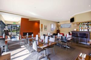 un restaurante con mesas y sillas y un bar en Comfort Inn On Raglan, en Warrnambool