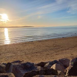 a beach with the sun setting over the water at Beautiful self-contained annex in Hoylake