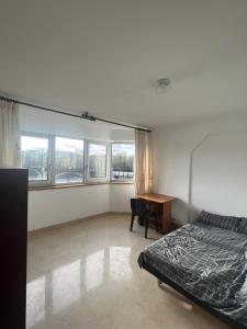 a bedroom with a bed and a desk and windows at Courbevoie Riverview in Courbevoie