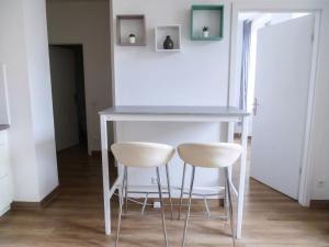 a table and two white stools in a room at Thiergarten - Charmant T2 à proximité de la gare in Strasbourg
