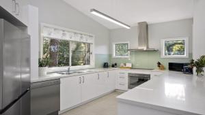 cocina blanca con armarios blancos y ventana en Bouddi Bush Retreat with Bay Views, en Booker Bay